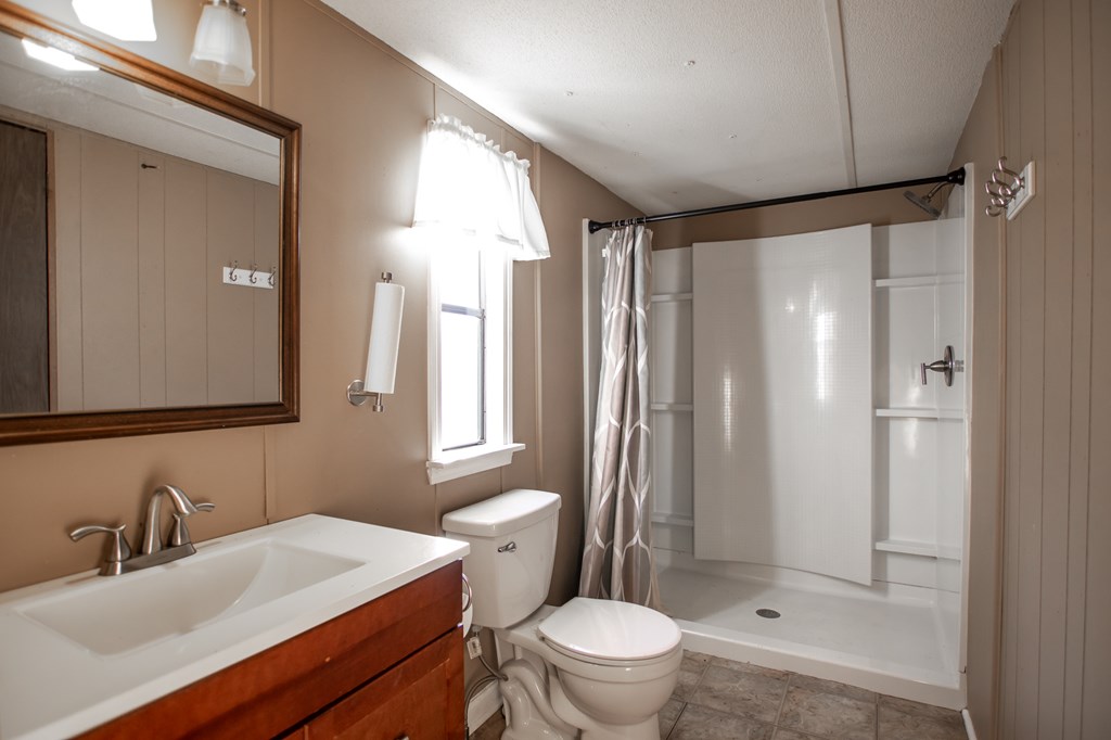 1631 West Pine Lake Drive West Point, GA 31833 - Photo 19 of 37 a bathroom with a sink a toilet a mirror and a shower