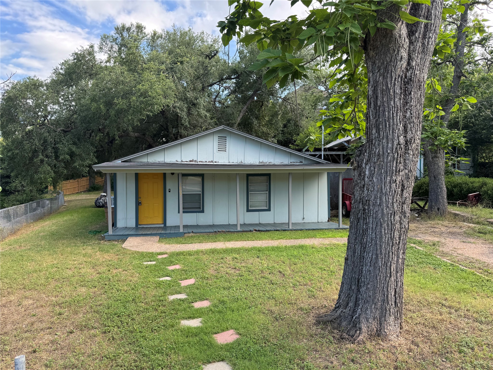 5007 Heflin Lane Austin, TX 78721 - Photo 1 of 25 A cheerful yellow door welcomes you to this cozy home nestled among mature trees.