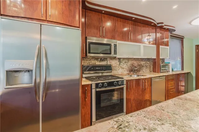 a large kitchen with stainless steel appliances kitchen island granite countertop a large window and cabinets