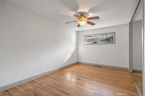 a view of an empty room with wooden floor and a chandelier