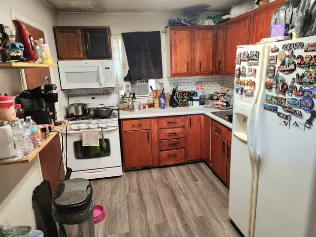 a kitchen with stainless steel appliances a stove a sink dishwasher and a refrigerator with wooden floor