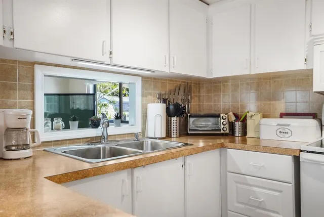 a kitchen with stainless steel appliances granite countertop a sink and a white cabinets