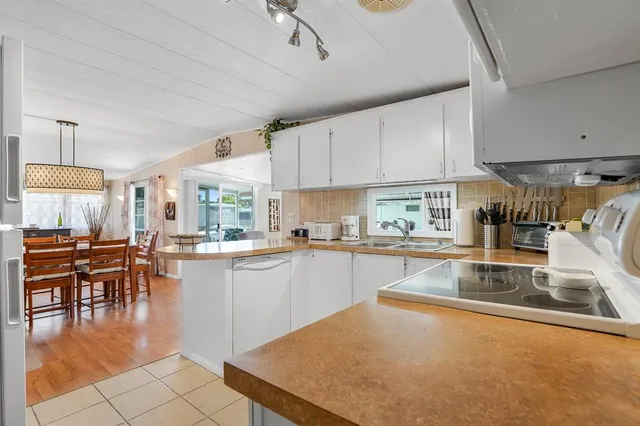 a kitchen with stainless steel appliances granite countertop a stove top oven a sink a dining table and chairs with white cabinets