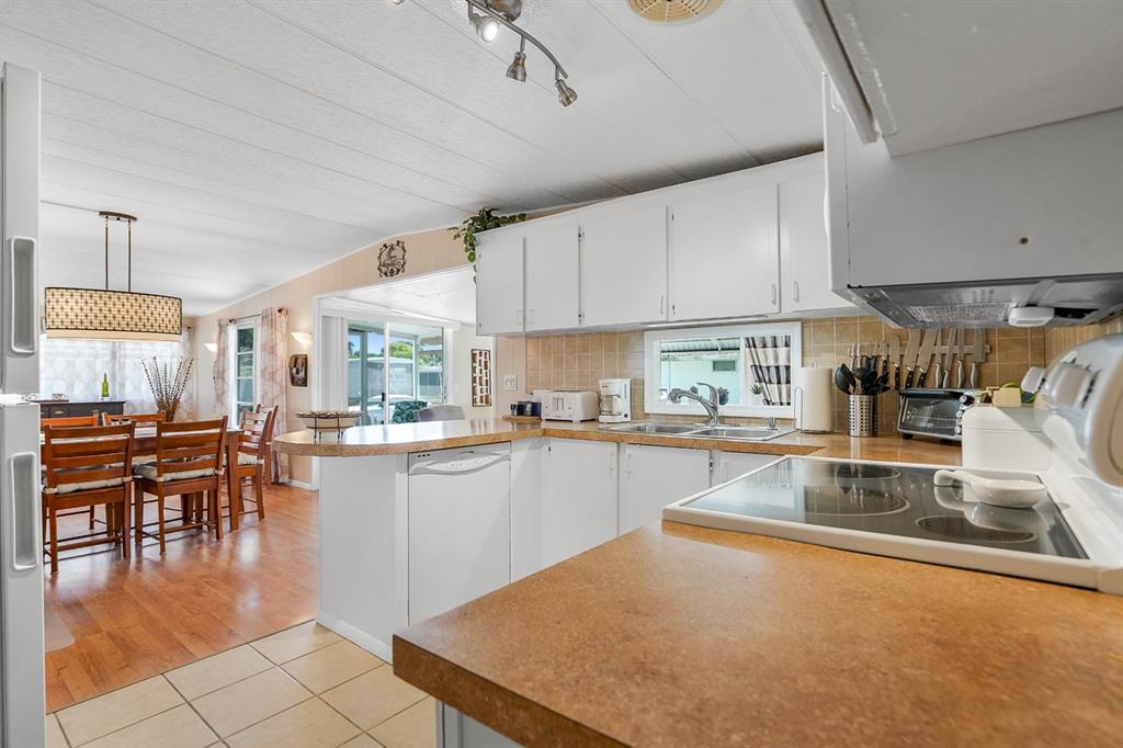 2001 Southwest 84th Avenue Davie, FL 33324 - Photo 17 of 38 a kitchen with stainless steel appliances granite countertop a stove top oven a sink a dining table and chairs with white cabinets