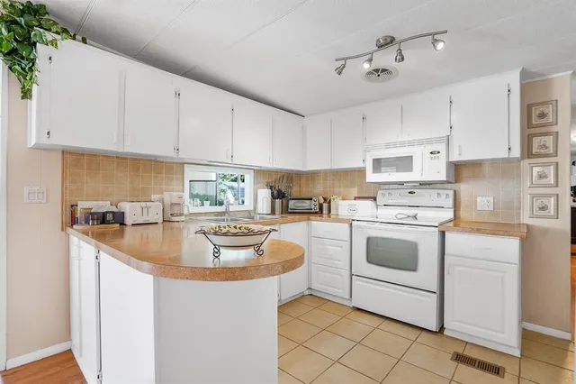 a kitchen with kitchen island granite countertop a sink a stove and white cabinets