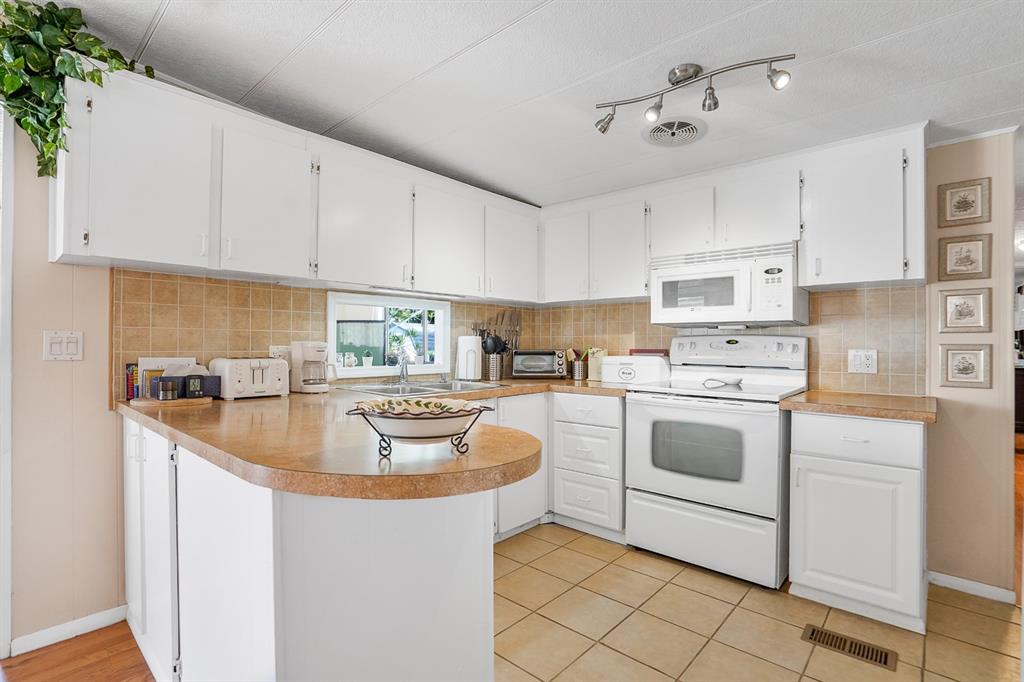 2001 Southwest 84th Avenue Davie, FL 33324 - Photo 2 of 38 a kitchen with kitchen island granite countertop a sink a stove and white cabinets