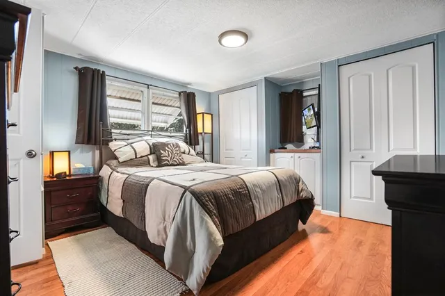 a bedroom with a bed and a dresser with wooden floor