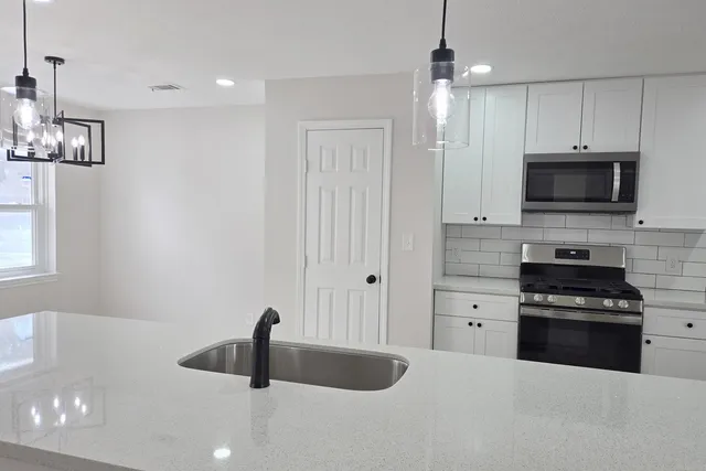 a kitchen with stainless steel appliances a sink a stove and microwave