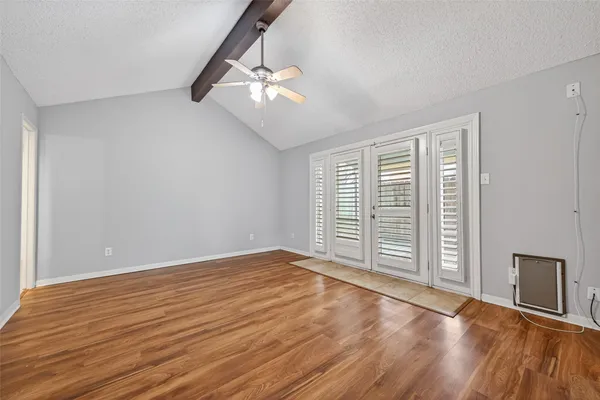 a view of an empty room with wooden floor and a window