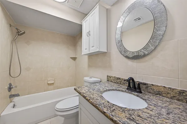a bathroom with a granite countertop sink a toilet and a mirror