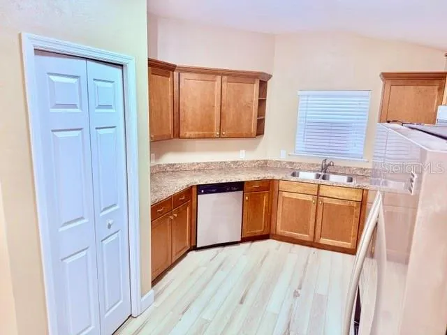 a kitchen with stainless steel appliances granite countertop a sink and wooden cabinets