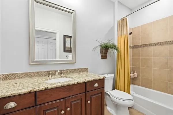 a bathroom with a granite countertop bathtub sink vanity mirror and toilet
