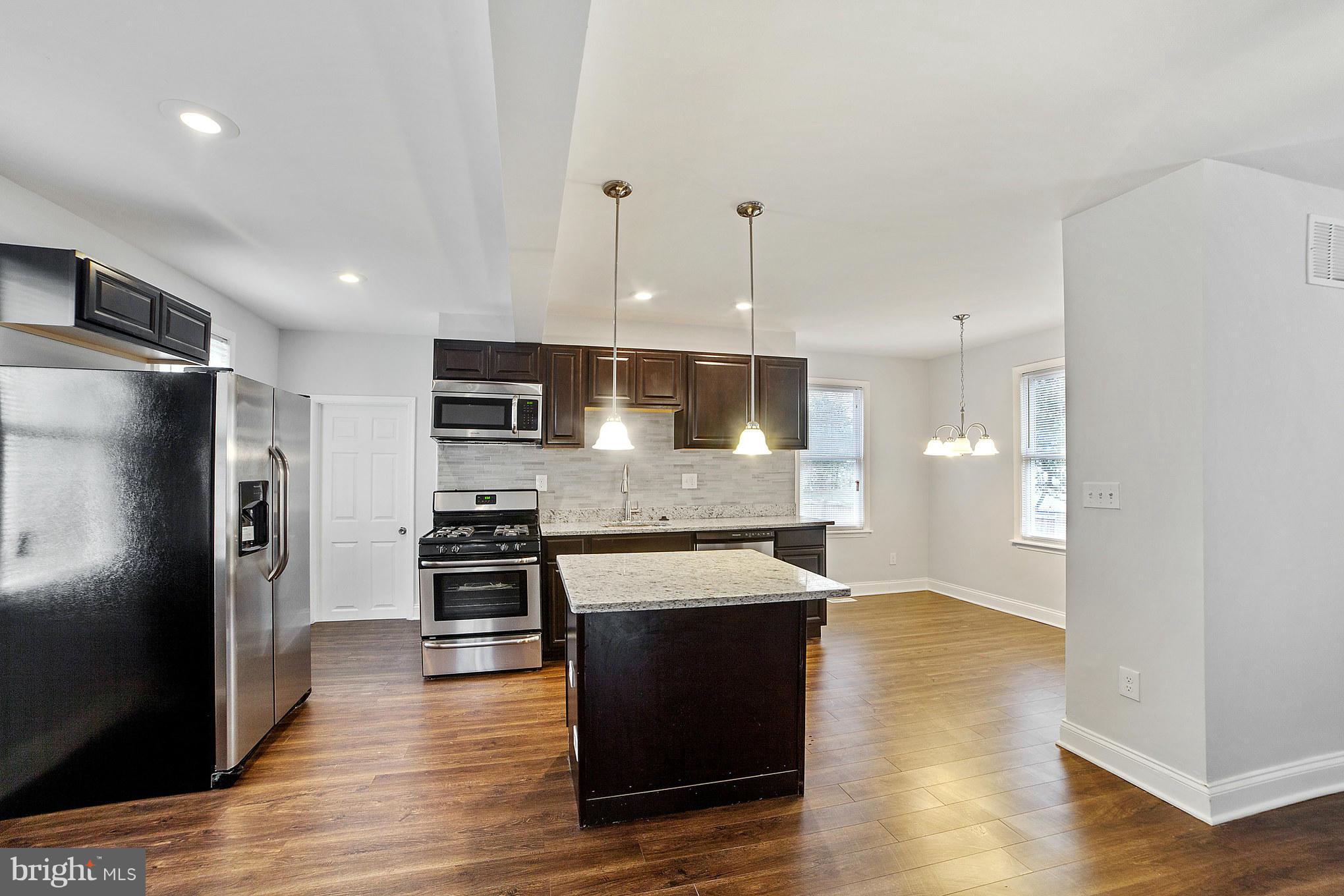 5502 Tramore Road Baltimore, MD 21214 - Photo 1 of 30 a large kitchen with stainless steel appliances granite countertop a refrigerator a sink a stove and oven with wooden floor