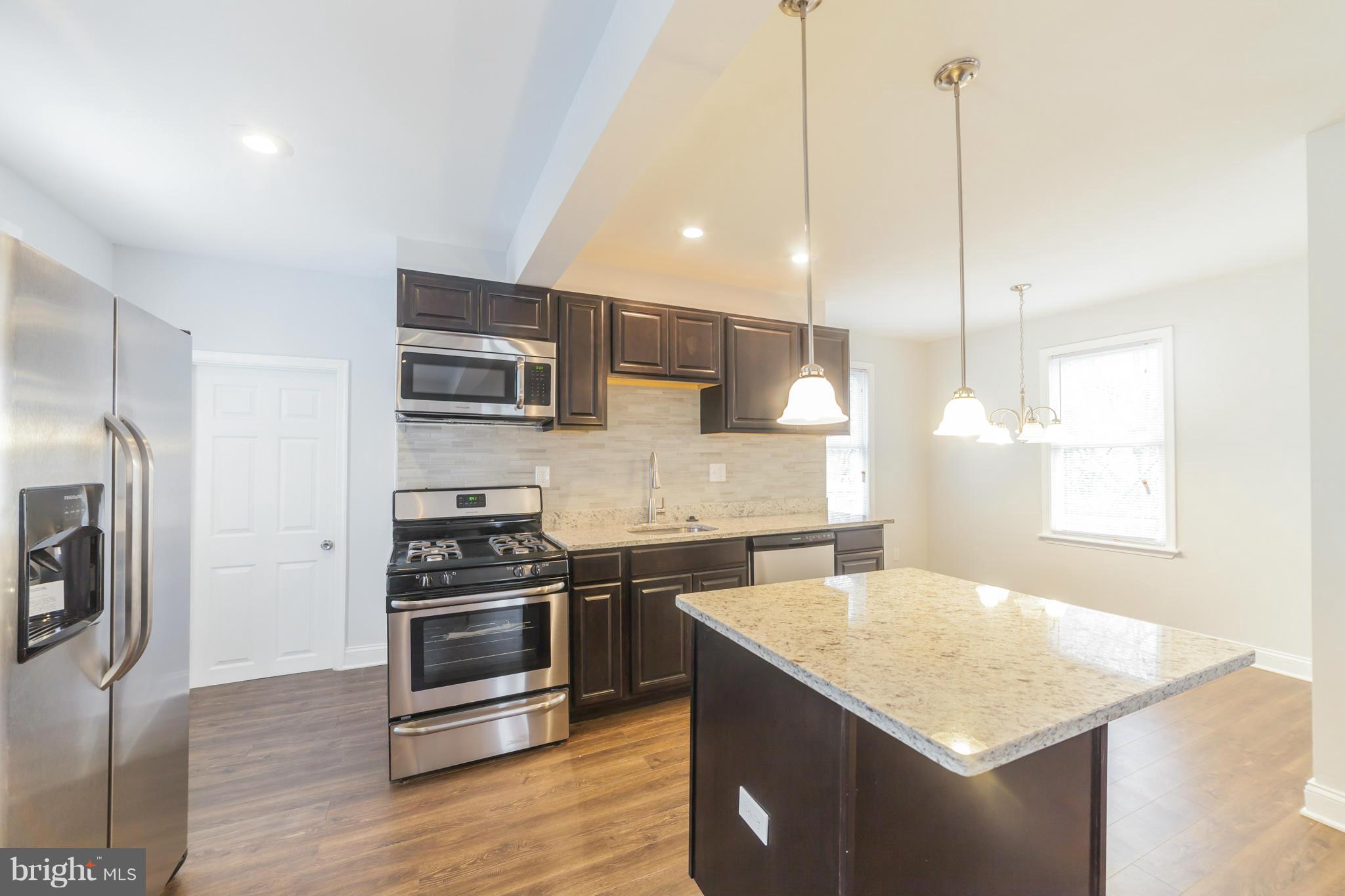 5502 Tramore Road Baltimore, MD 21214 - Photo 13 of 30 a kitchen with stainless steel appliances granite countertop a sink a stove a refrigerator and a oven with wooden floor