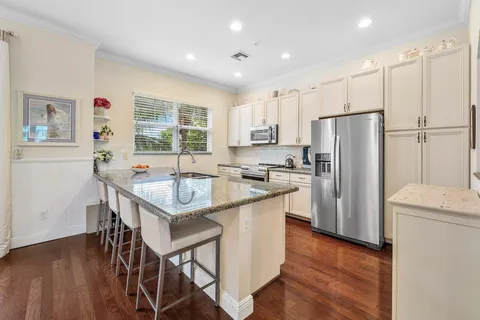a kitchen with stainless steel appliances granite countertop a refrigerator a sink a stove a dining table and chairs