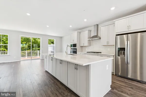 a kitchen with stainless steel appliances granite countertop a refrigerator a sink dishwasher a stove and white countertops with wooden floor