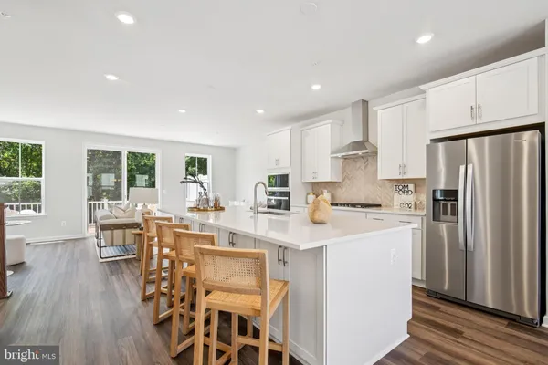 a kitchen with stainless steel appliances a dining table chairs refrigerator and wooden cabinets