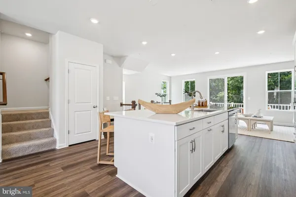a large white kitchen with white cabinets and wooden floor