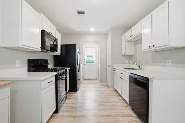 a kitchen with stainless steel appliances granite countertop a refrigerator a stove top oven a sink and dishwasher with wooden floor