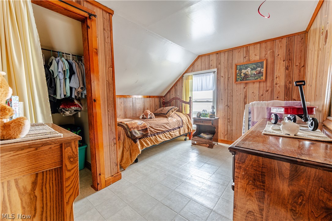 16350 Nauvoo Road Middlefield, OH 44062 - Photo 31 of 50 Bedroom with light floors, wood walls, lofted ceiling, and a spacious closet
