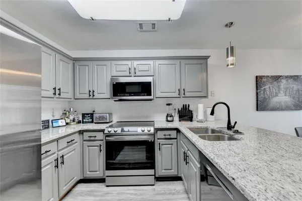 a kitchen with stainless steel appliances granite countertop a sink dishwasher a stove and a microwave oven with cabinets
