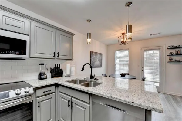 a kitchen with stainless steel appliances granite countertop a sink a stove and cabinets