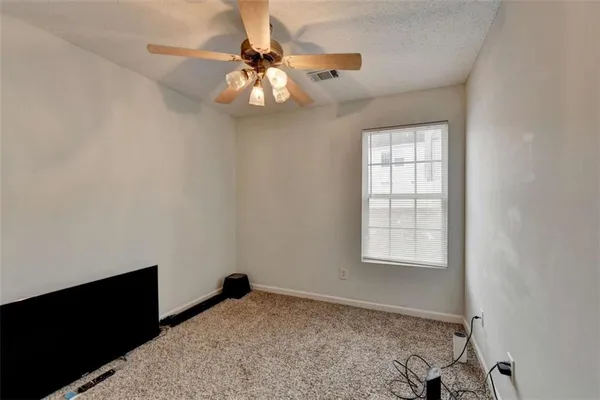 an empty room with windows and fan