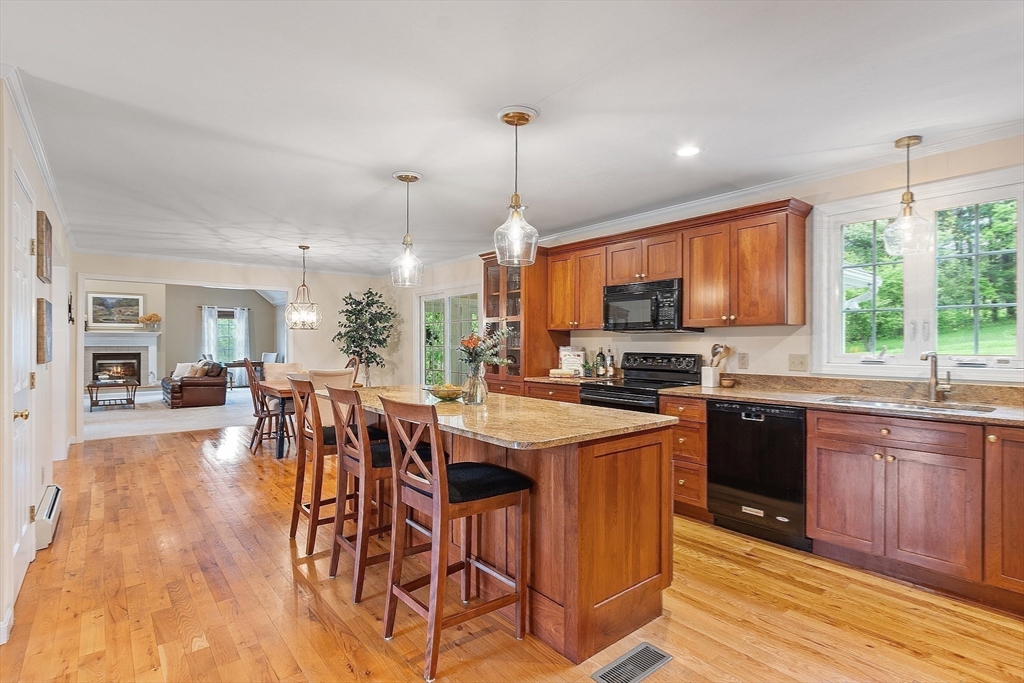 86 South Cross Road Haverhill, MA 01835 - Photo 11 of 42 a open kitchen with stainless steel appliances granite countertop a stove top oven a sink dishwasher a dining table and chairs with wooden floor