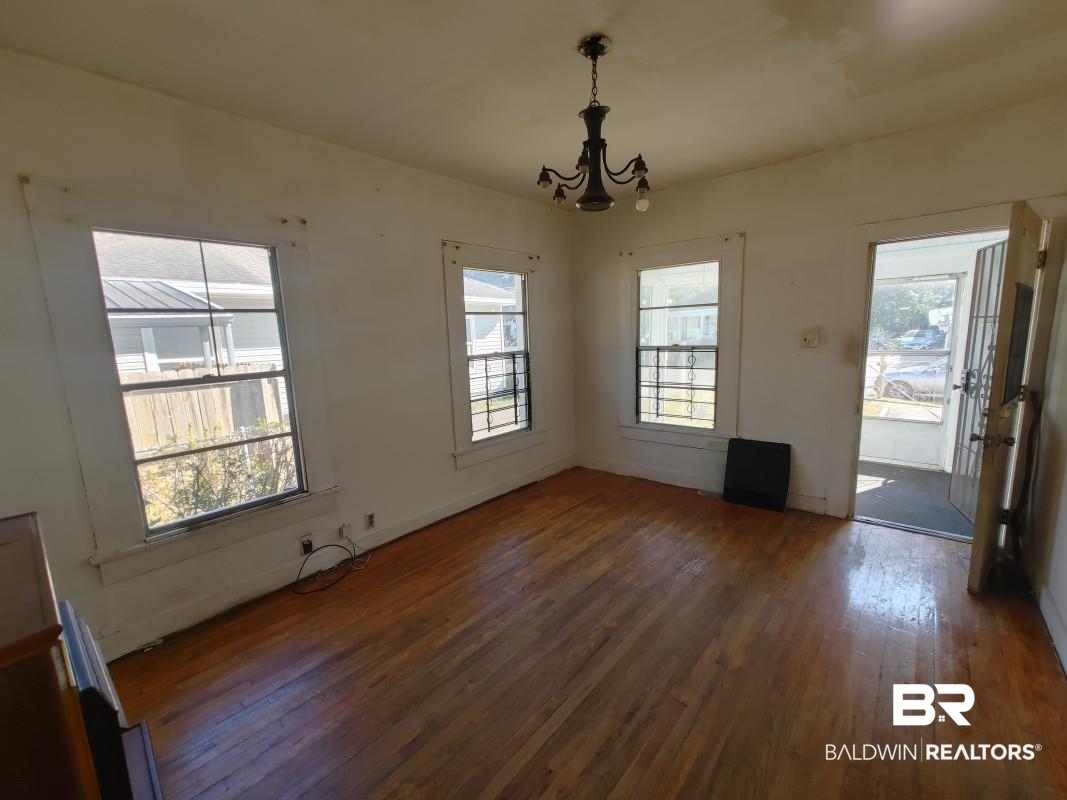 1706 Lomeroy Street Mobile, AL 36604 - Photo 8 of 24 Unfurnished dining area with a chandelier and dark wood finished floors