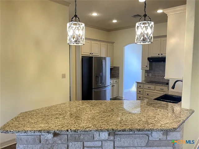 a kitchen with kitchen island granite countertop a refrigerator and a sink