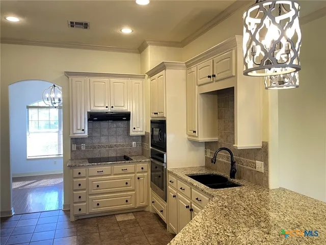 a kitchen with granite countertop a sink stainless steel appliances and cabinets