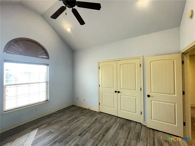 an empty room with wooden floor cabinet and windows