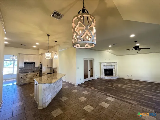 a large kitchen with stainless steel appliances granite countertop a stove and a view of living room
