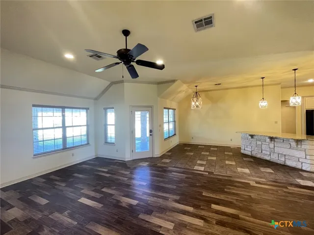 a view of an empty room with window and wooden floor