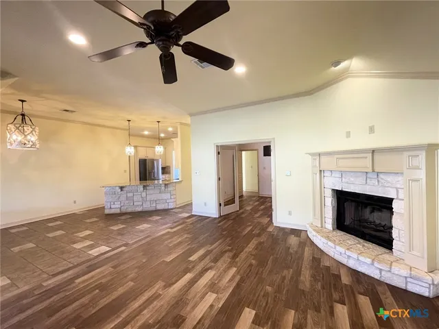 a view of a livingroom with a fireplace a ceiling fan and brick wall