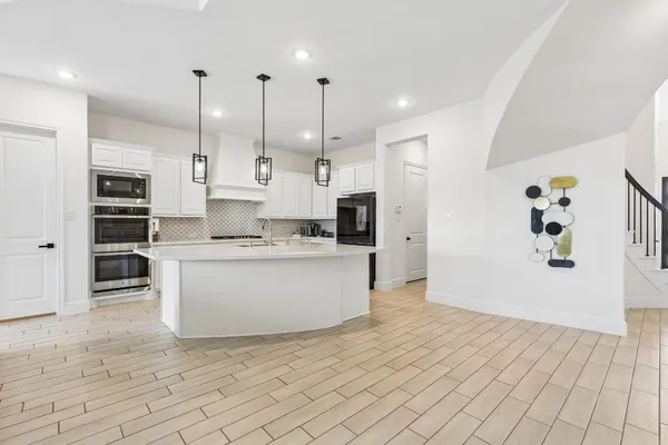 a large kitchen with stainless steel appliances kitchen island granite countertop a refrigerator a oven a sink and white cabinets