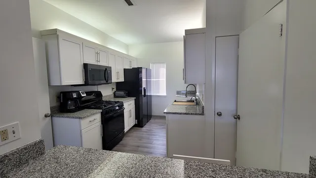 a kitchen with granite countertop a sink a counter top space cabinets and stainless steel appliances