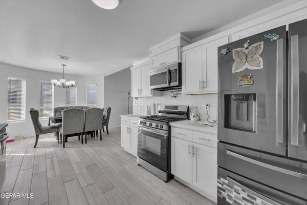 a kitchen with stainless steel appliances granite countertop a stove top oven a sink and white cabinets