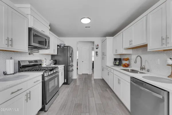a kitchen with stainless steel appliances granite countertop a stove top oven a sink dishwasher a refrigerator and cabinets with wooden floor