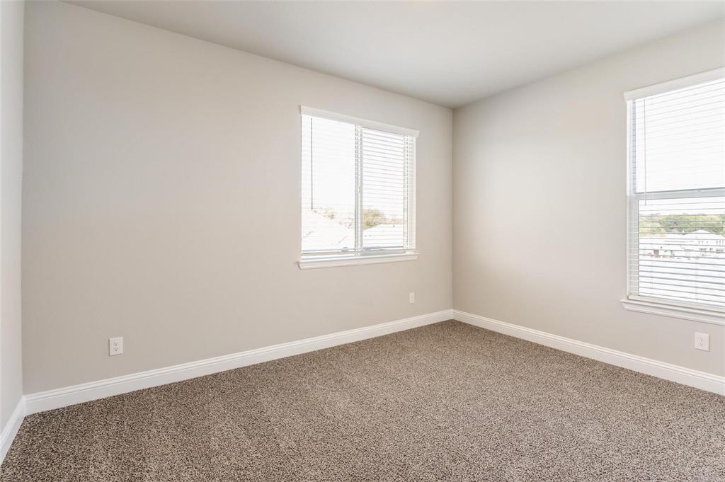 1517 Razorbill Road Denton, TX 76205 - Photo 22 of 25 Neutral-toned walls, plush carpet flooring, two windows with blinds, and white trim accents