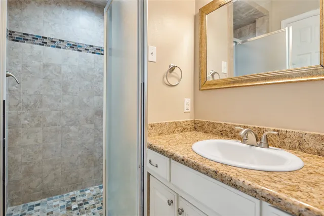 a bathroom with a granite countertop sink a mirror and a shower