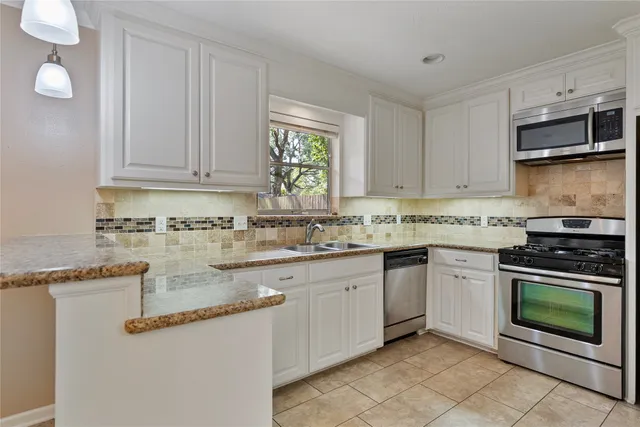 a kitchen with granite countertop a stove sink and cabinets