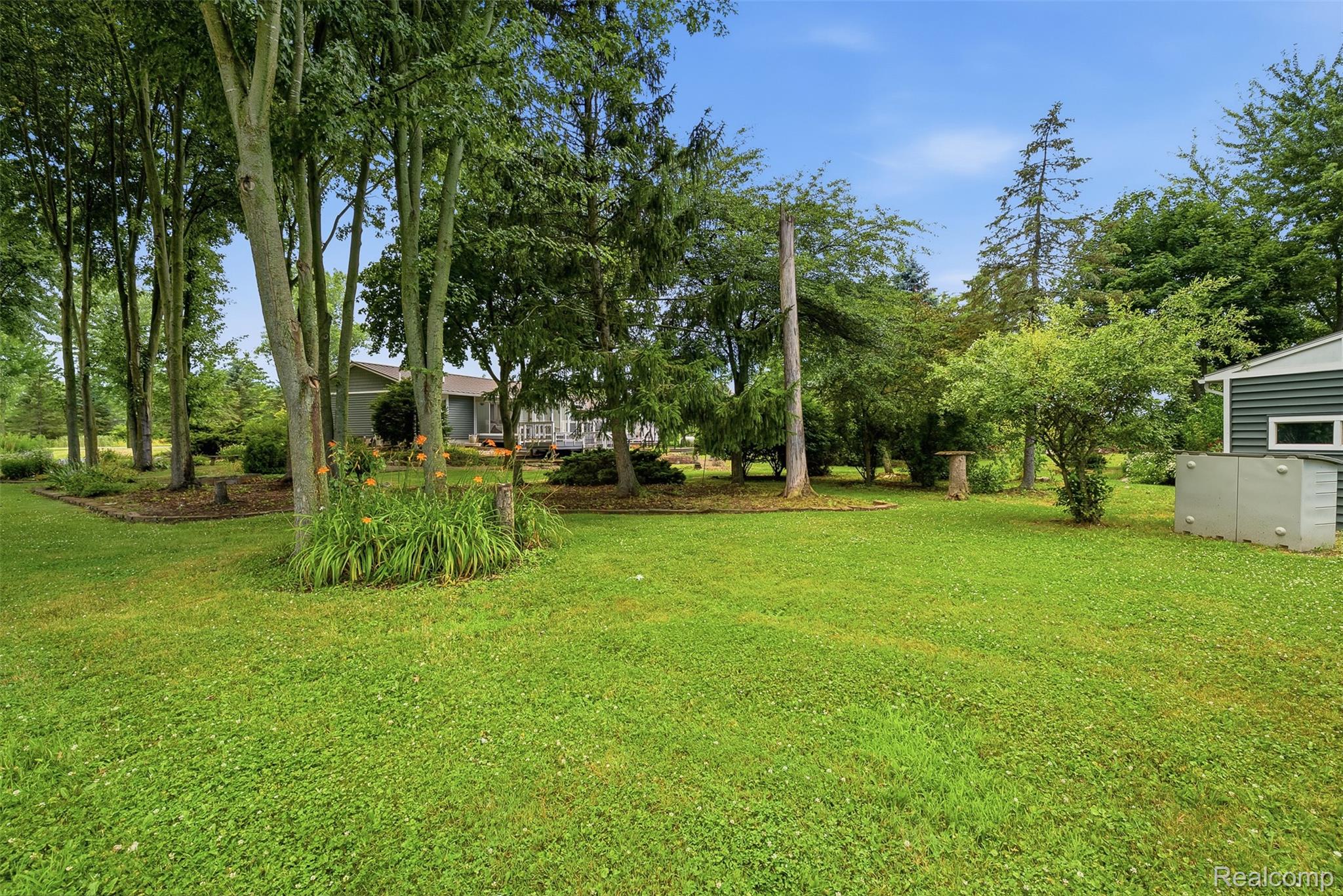 13182 Gilbert Road Memphis, MI 48041 - Photo 37 of 48 Expansive green lawn surrounded by mature trees, featuring a landscaped garden area with blooming perennials