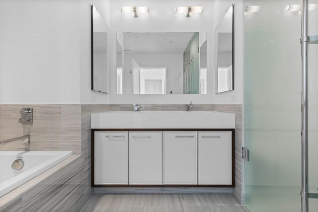 a bathroom with a sink a bathtub a mirror and vanity