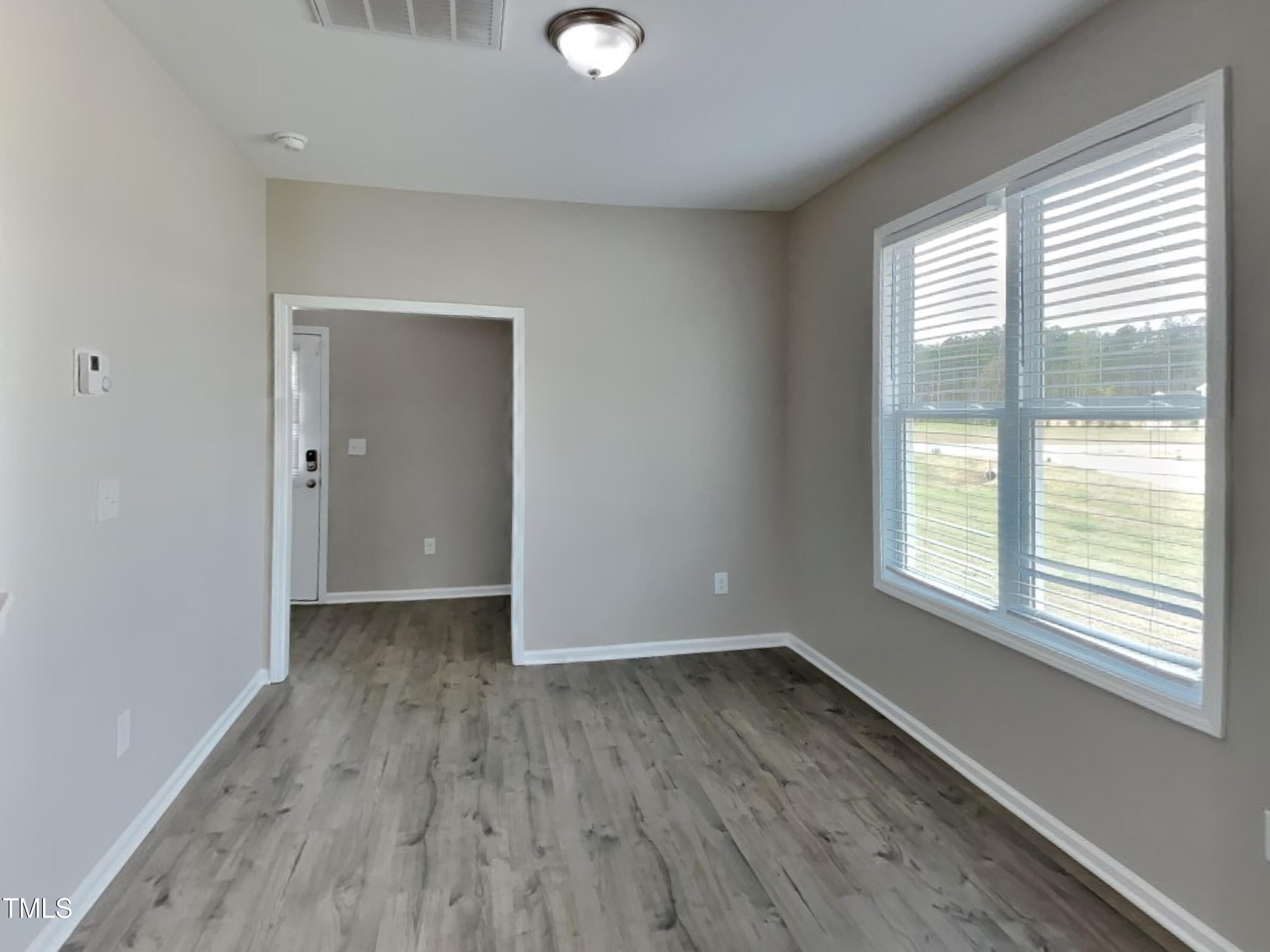 376 Olde Place Drive Zebulon, NC 27597 - Photo 5 of 16 a view of an empty room with wooden floor and a window