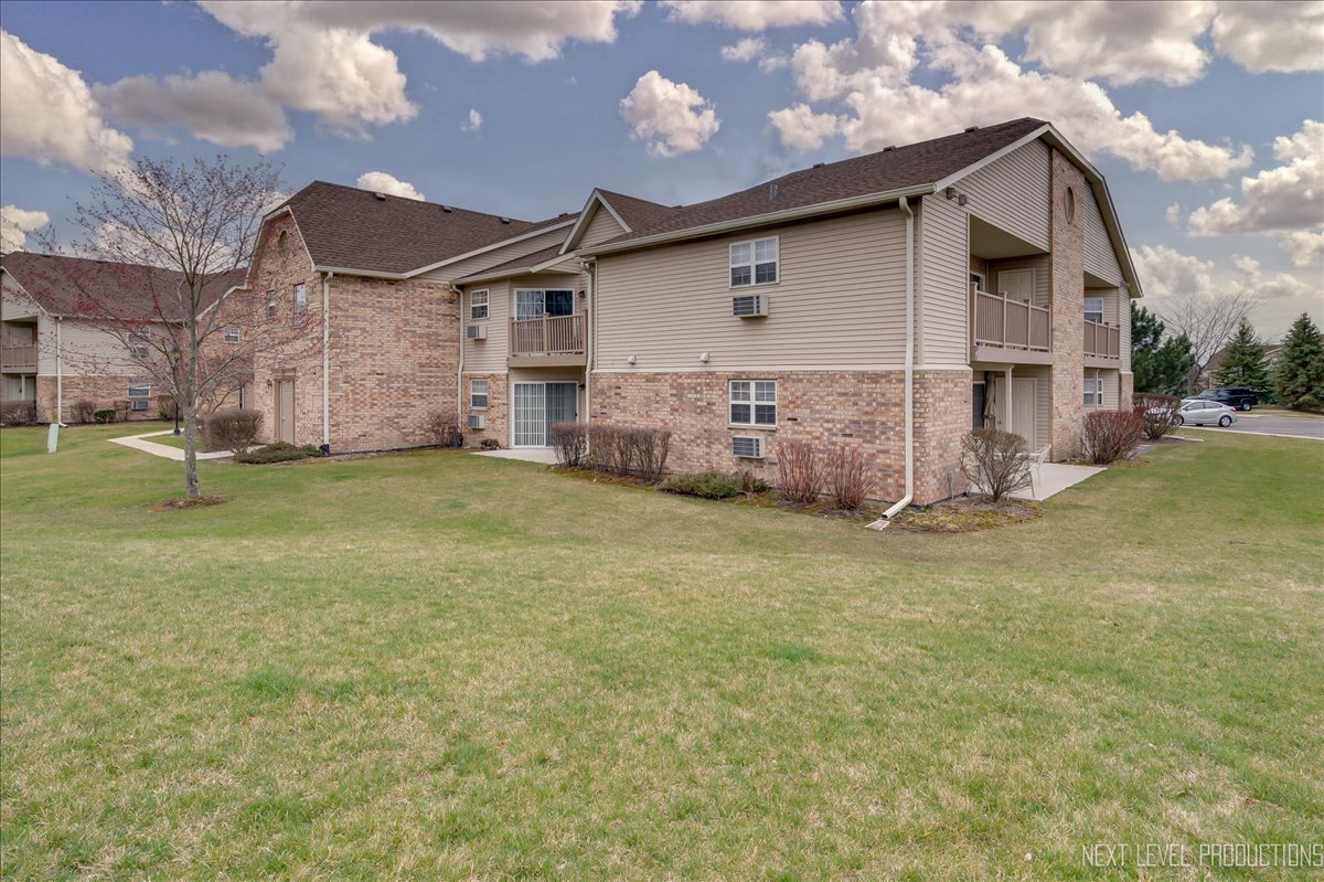 1506 Spring Brook Court, Unit 2A Round Lake Beach, IL 60073 - Photo 2 of 13 a front view of house with yard and trees in the background