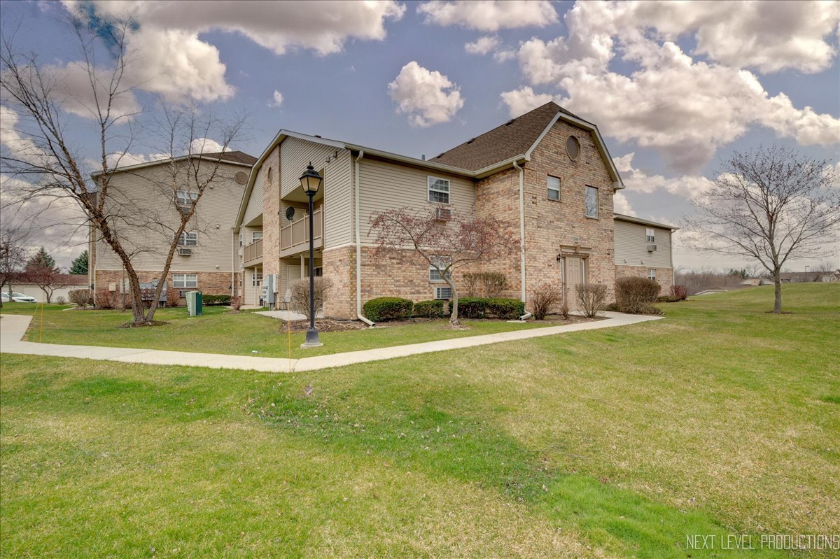 1506 Spring Brook Court, Unit 2A Round Lake Beach, IL 60073 - Photo 4 of 13 a front view of a building with a garden