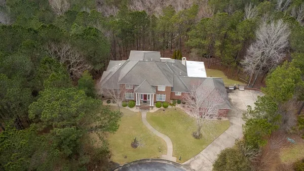 an aerial view of a house with swimming pool and large trees