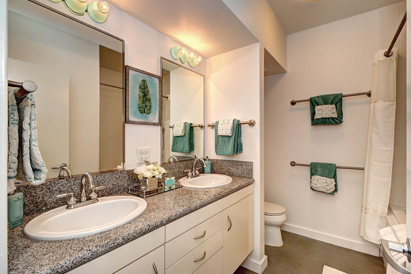 334 Santana Row, Unit 304 San Jose, CA 95128 - Photo 17 of 18 a bathroom with a granite countertop sink a toilet a mirror and shower