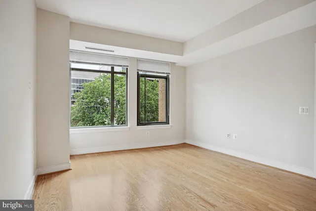 an empty room with wooden floor and windows